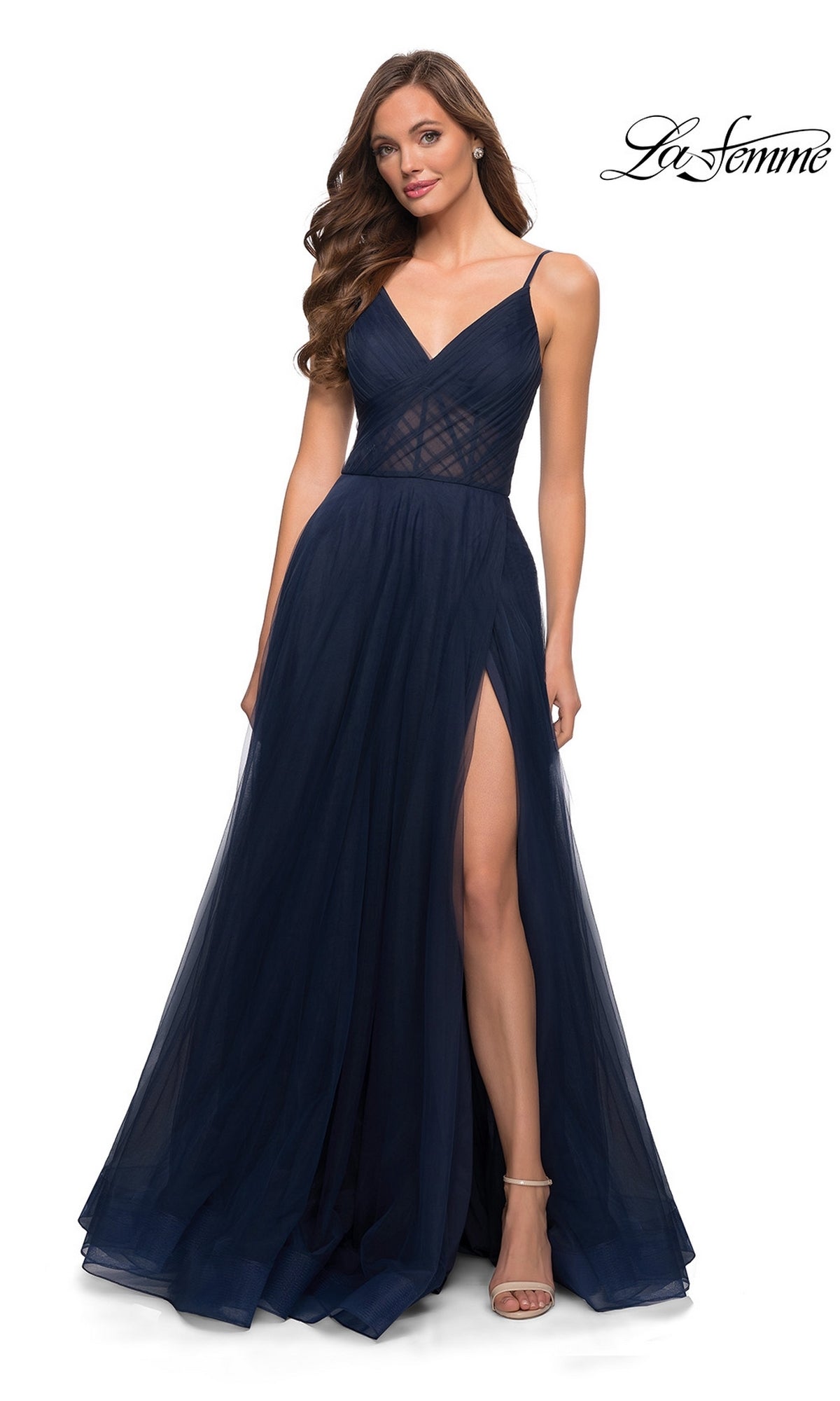 Woman in a La Femme Sheer-Waist Long A-Line Prom Dress 29076, featuring a navy blue tulle skirt, deep V-neckline, sheer bodice, and high slit, posed against a white background.